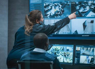 Female,Security,Worker,Talks,With,African,American,Colleague,,Uses,Tablet.